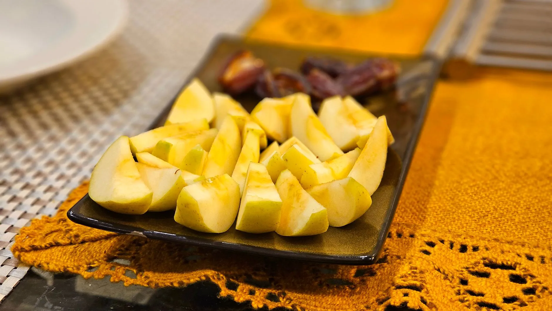A close-up of sliced apples with dates on a decorative plate.