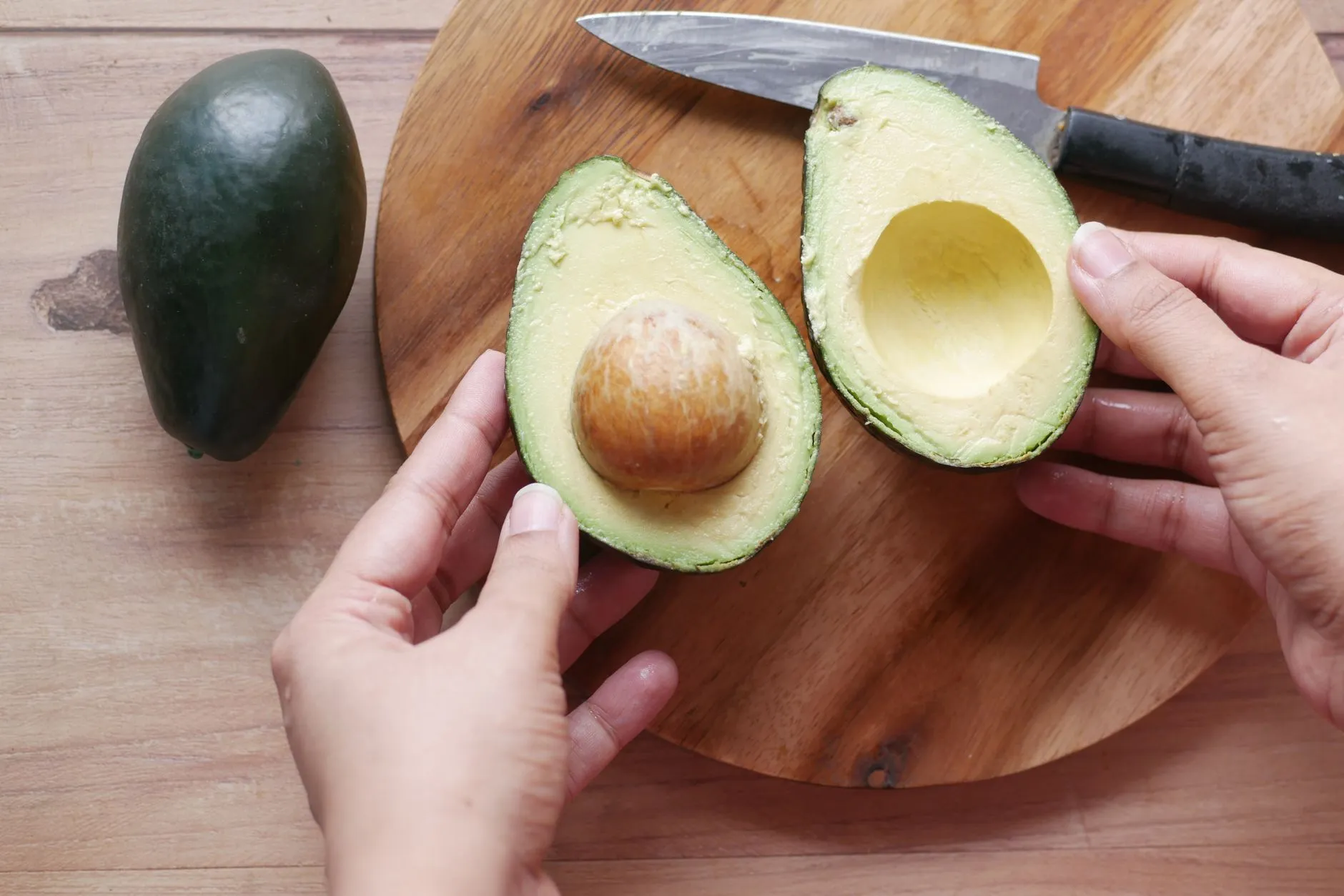 Freshly sliced avocado halves on a wooden board, showcasing its creamy texture and seed.