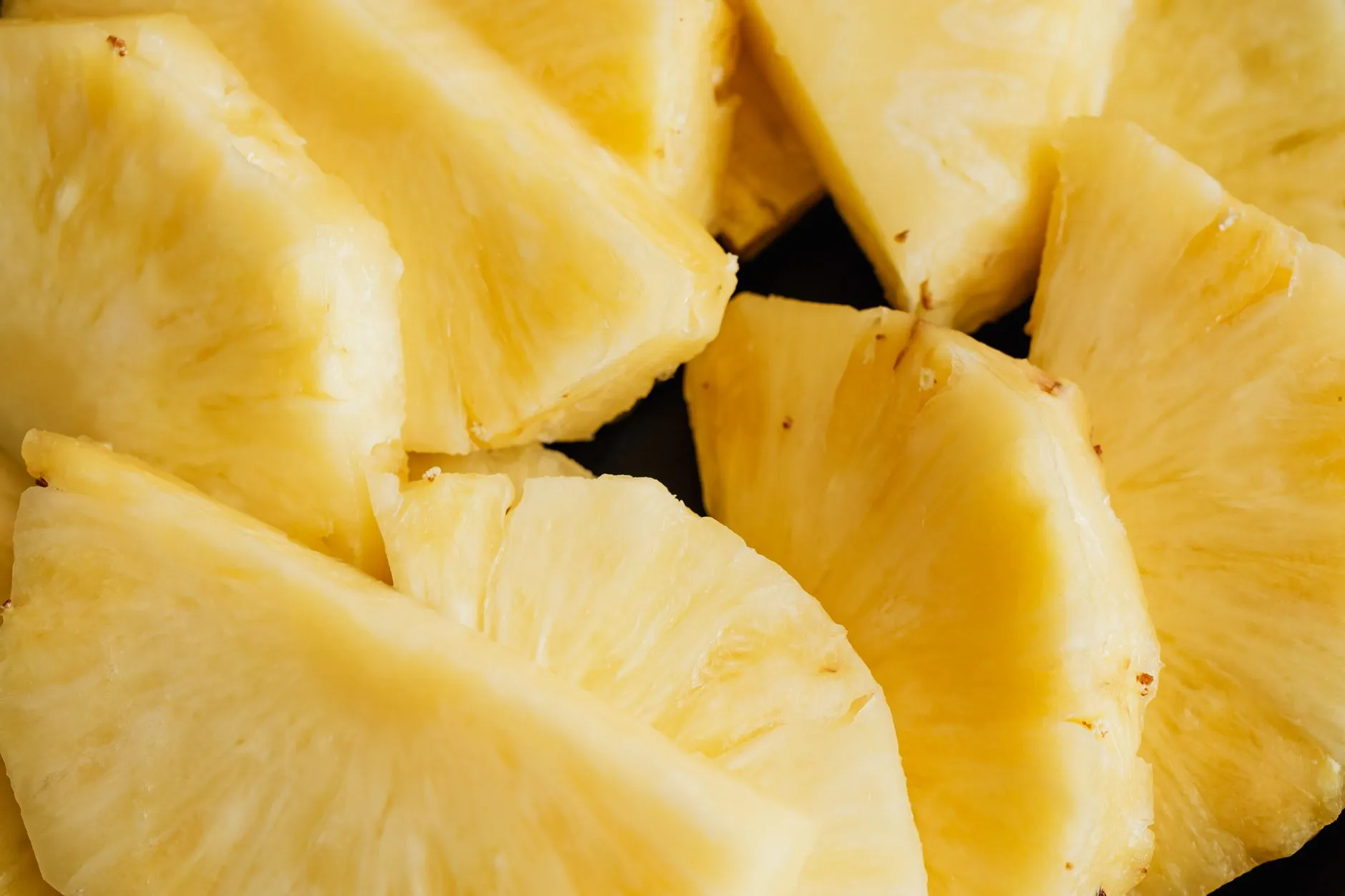 From above of ripe fresh sliced peeled fresh juicy pineapple served against black background