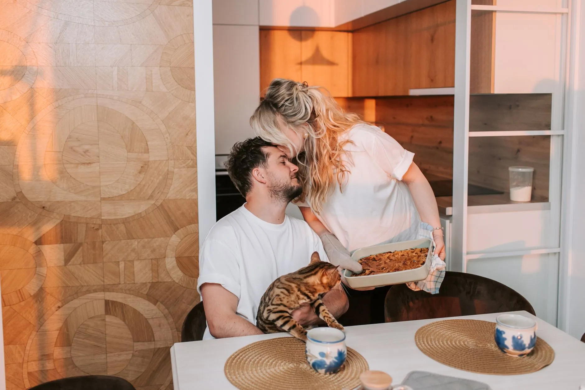 A loving couple sitting together with a cat and enjoying a cozy moment indoors.