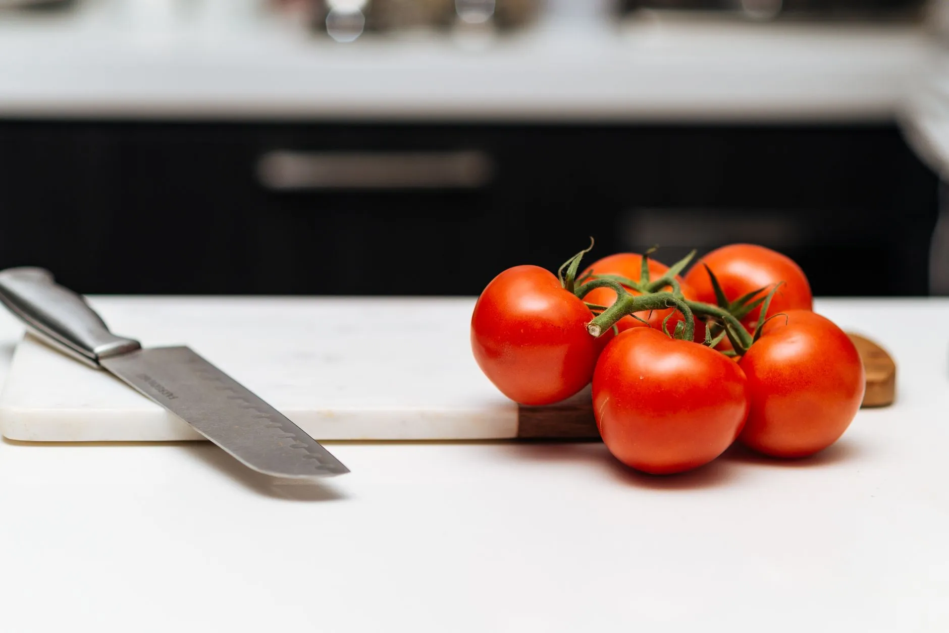 Close-up view of ripe tomatoes on a cutting board with a kitchen knife, perfect for culinary themes.
