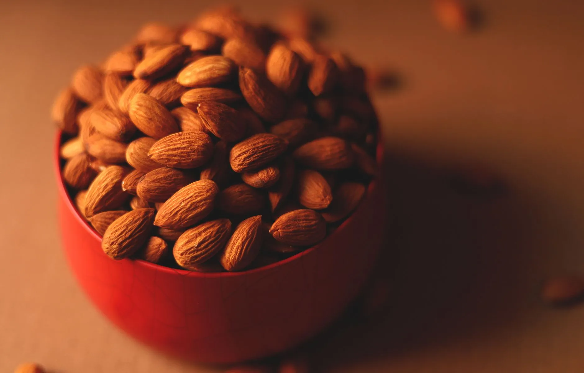 A close-up of almonds in a red bowl, perfect for a healthy snack or nutritious eating.