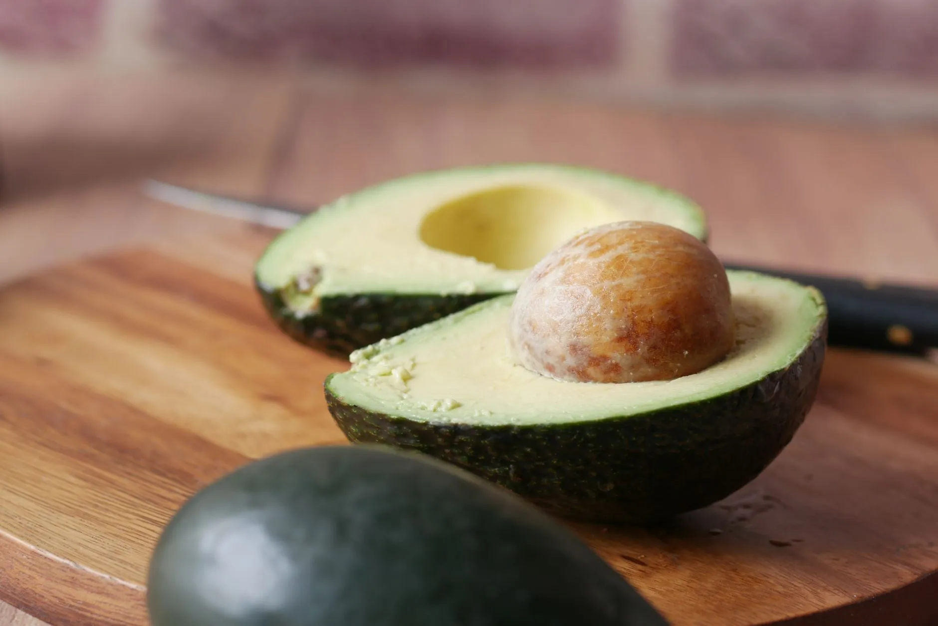 A close-up view of a fresh sliced avocado on a wooden cutting board, perfect for healthy recipes.