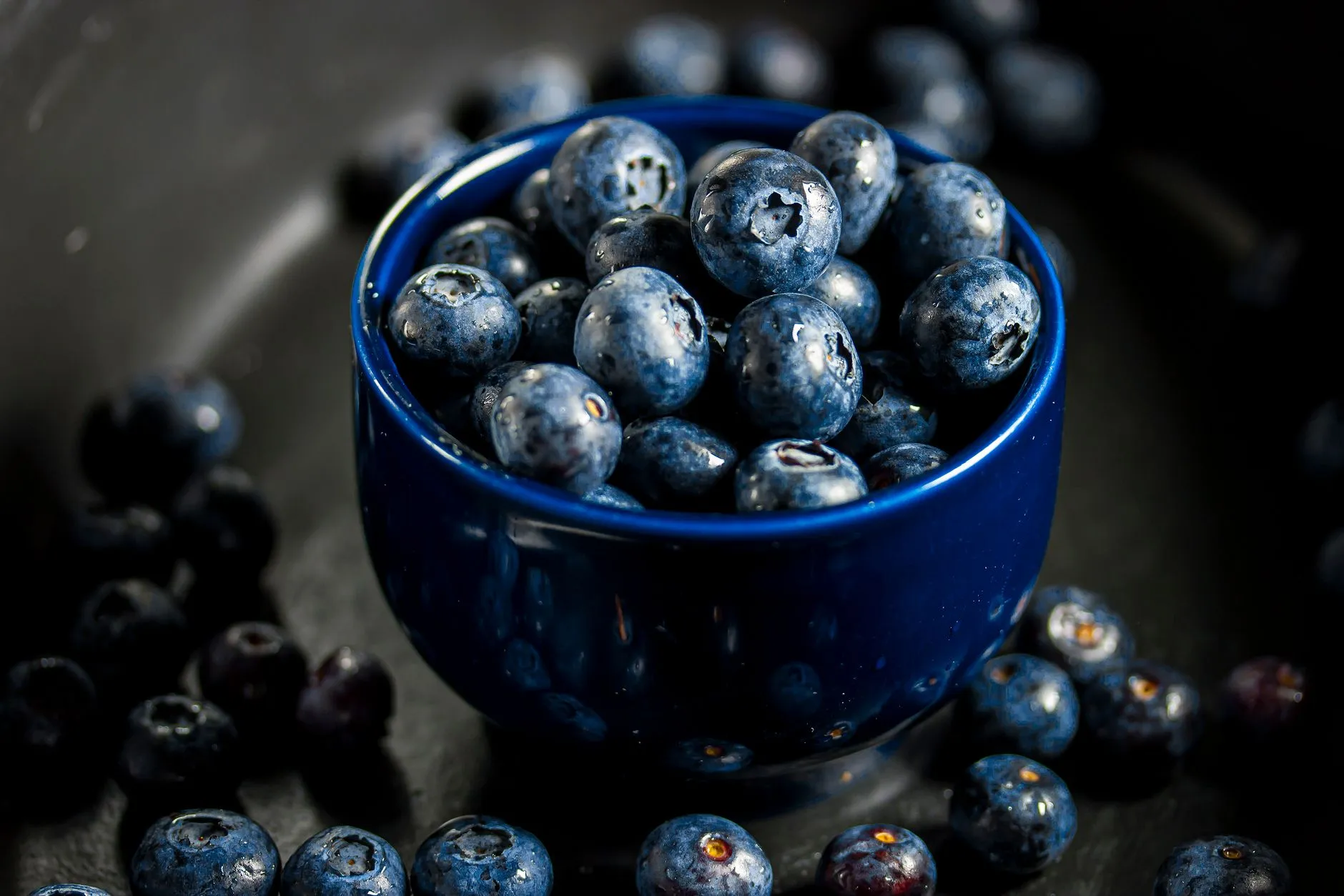 Vibrant blueberries in a dark blue bowl showcasing freshness.