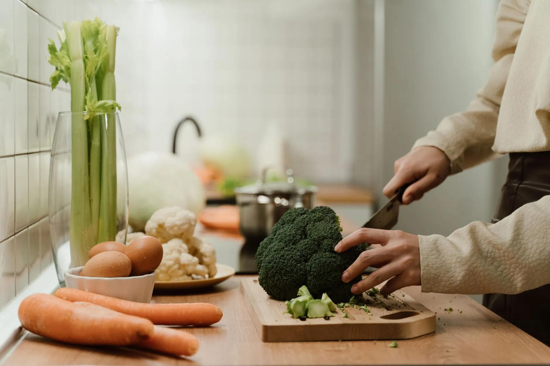 Fresh vegetables being chopped on a wooden board in a home kitchen setting.