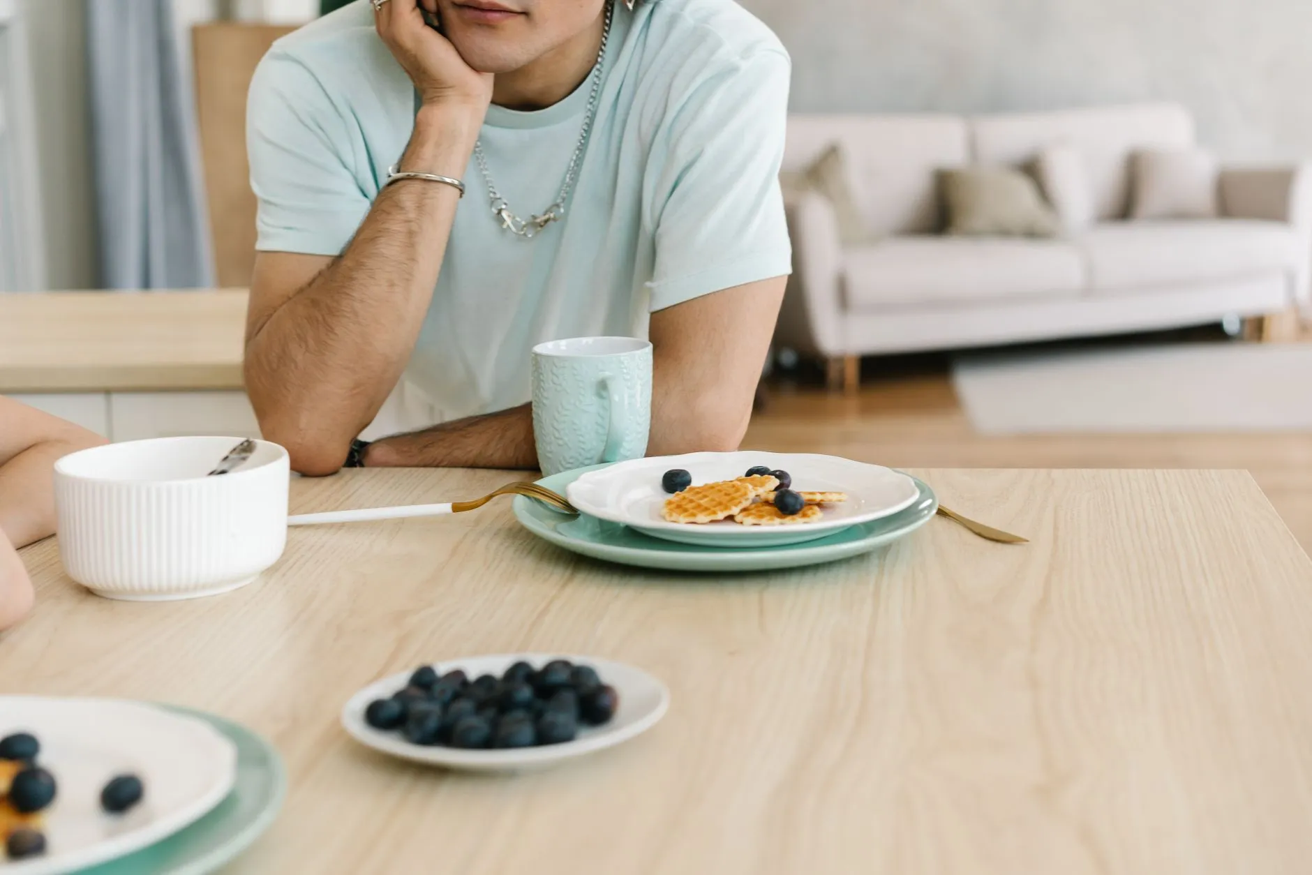 A relaxed indoor breakfast setting with waffles and blueberries on a wooden table.