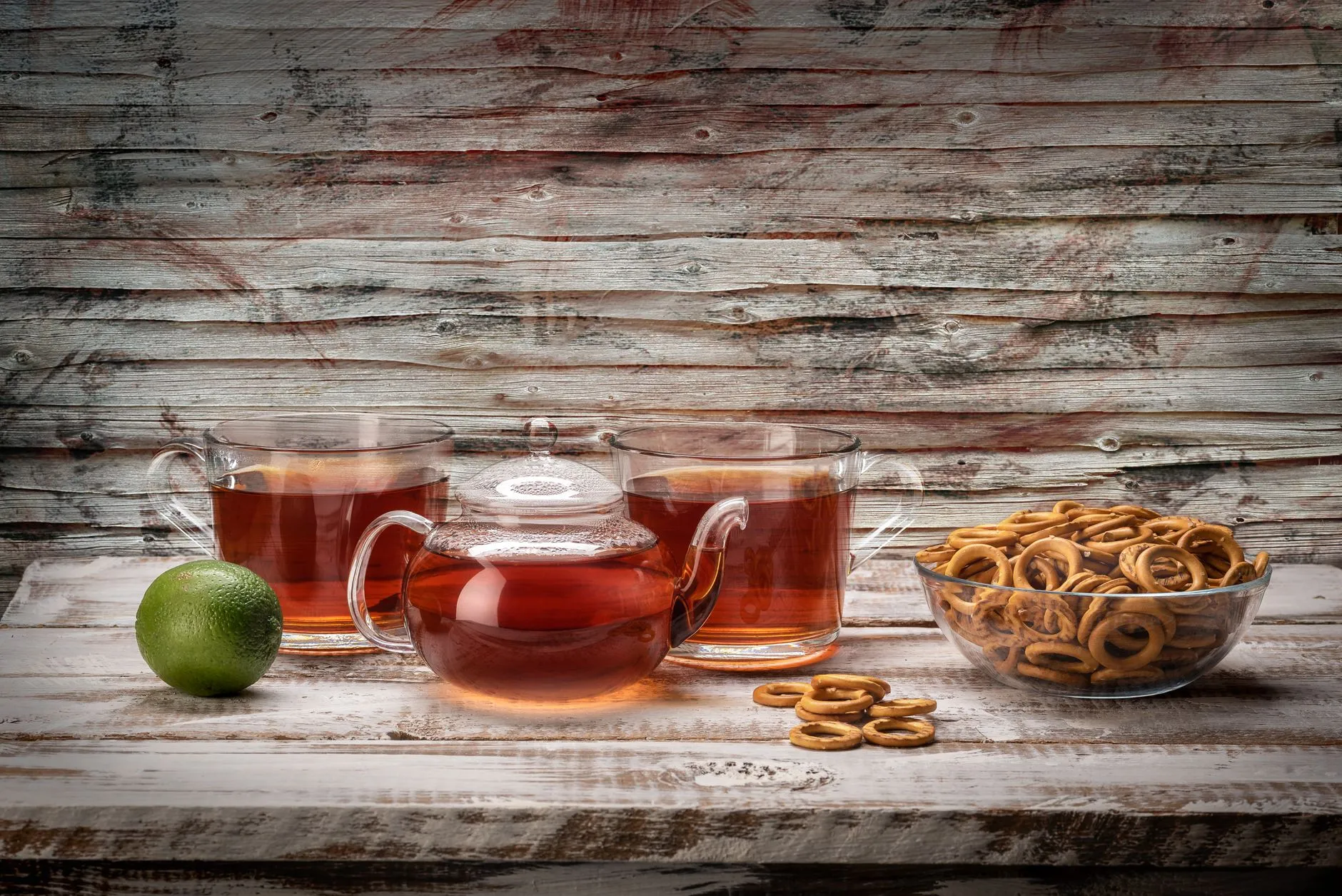 Rustic setup of tea, pretzels, and lime on wooden table, perfect for a relaxing break.