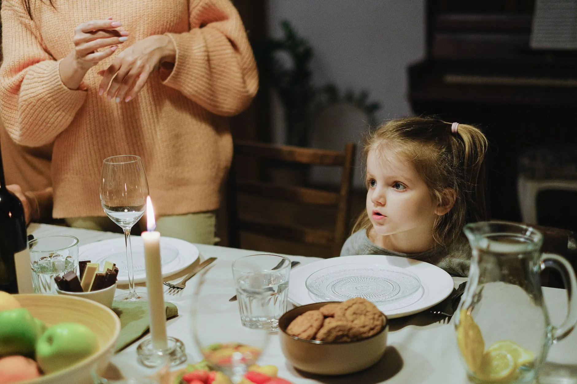 A warm, intimate family dinner setting with a child at the table, enjoying a cozy atmosphere.